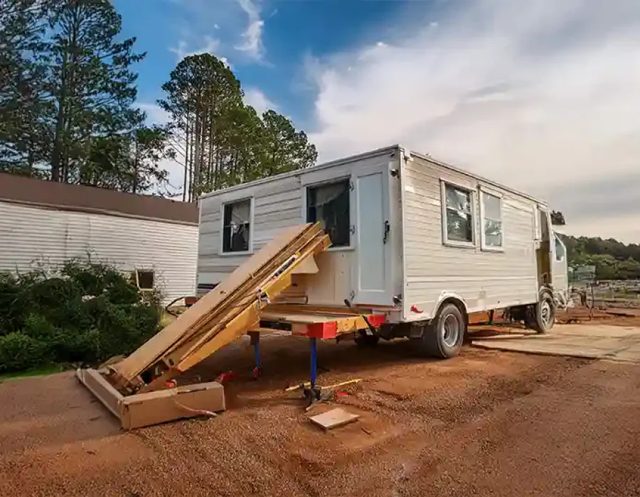 White trailer on stabilizing jacks with wooden ramps at construction demolition clearing site