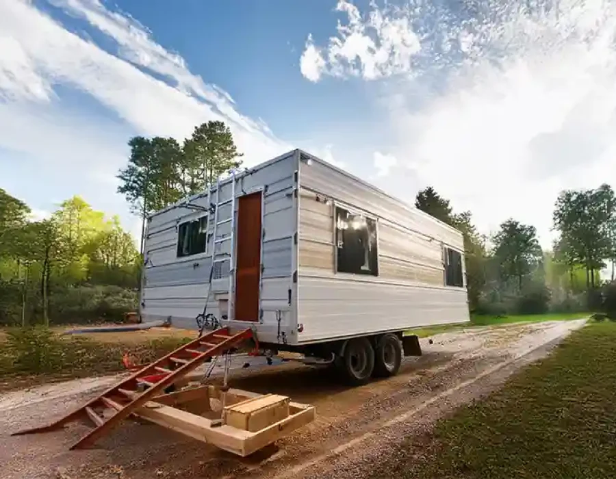 White trailer with red access stairs on cleared forest lot during construction site preparation