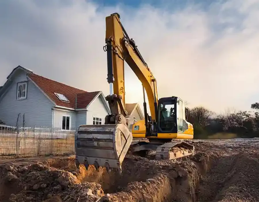 Excavator digging soil near a house for site preparation and demolition services.