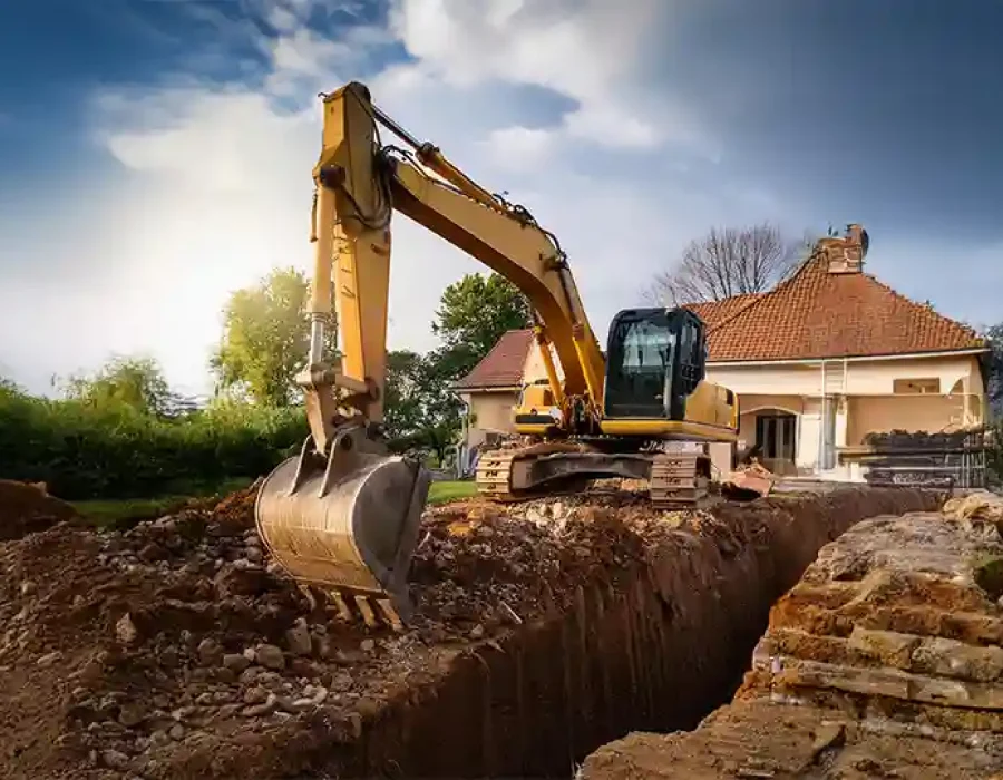 Excavator digging a trench near a house for site preparation and demolition services.