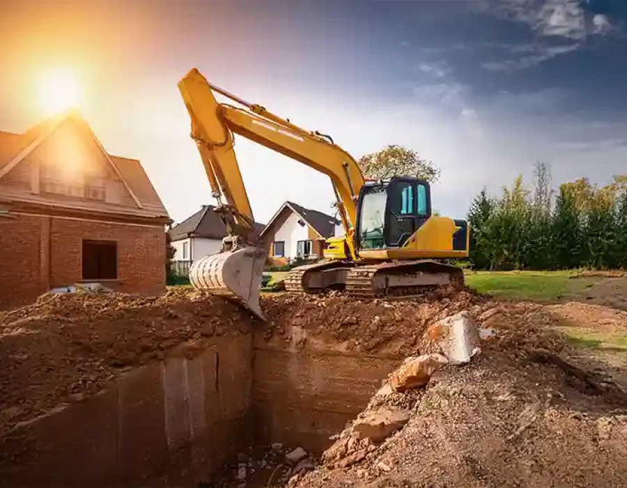 Excavator digging foundation near houses for demolition and site preparation.