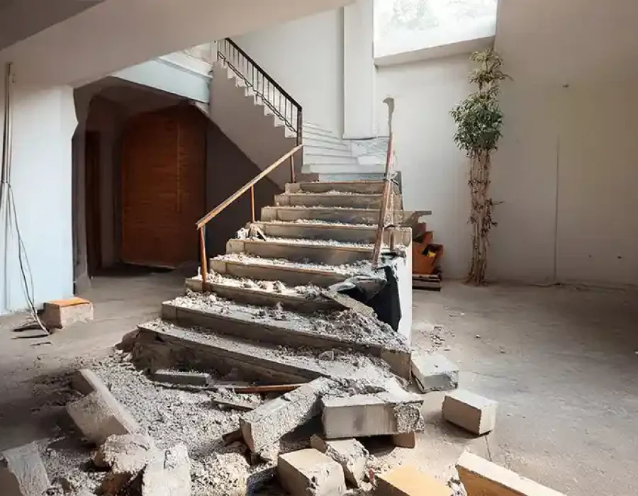 Partially demolished concrete staircase with debris and rubble during residential interior demolition project