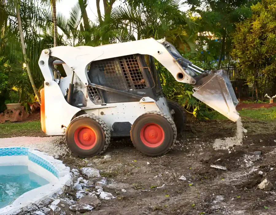 Skid steer loader clearing debris near a pool