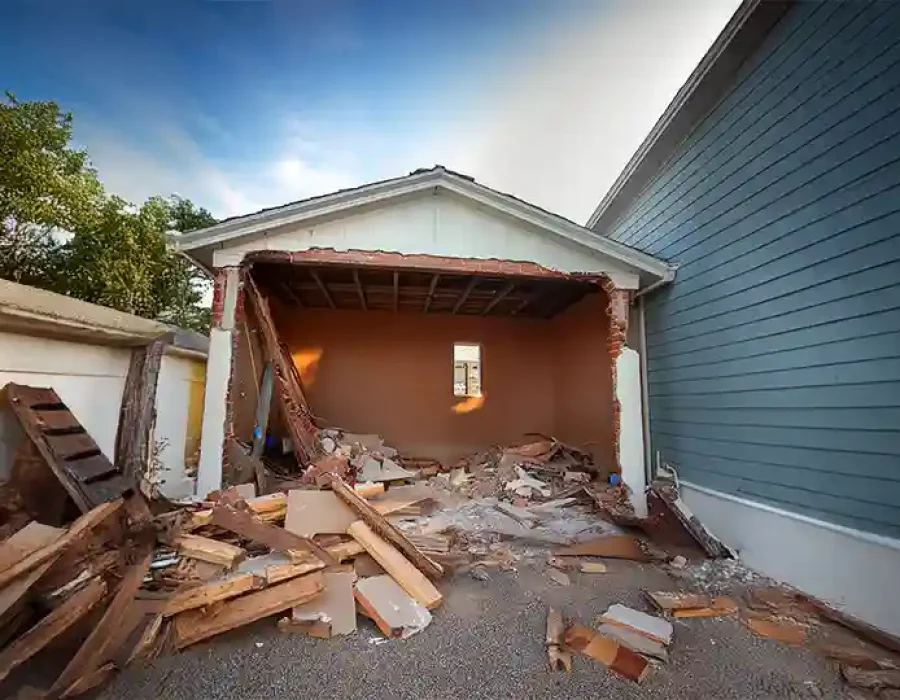A partially demolished garage with rubble and wood debris scattered around the site.