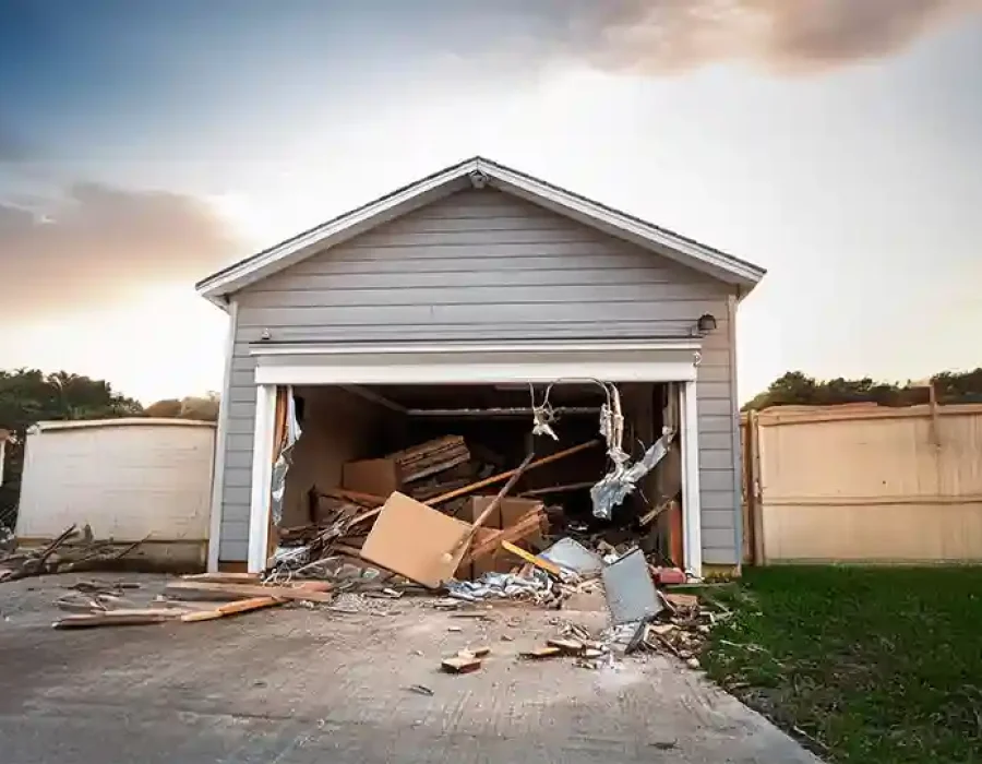 A partially demolished garage filled with rubble, wood, and debris scattered on the driveway.