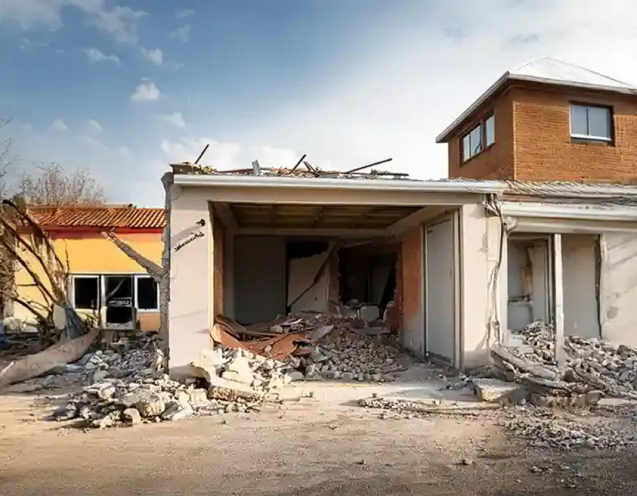 Partially demolished house with rubble and debris on-site.
