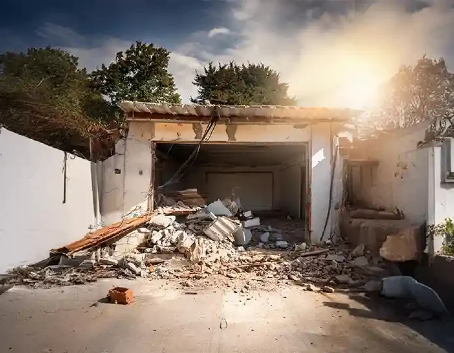 Partially demolished garage with rubble and debris ready for cleanup at a residential site.