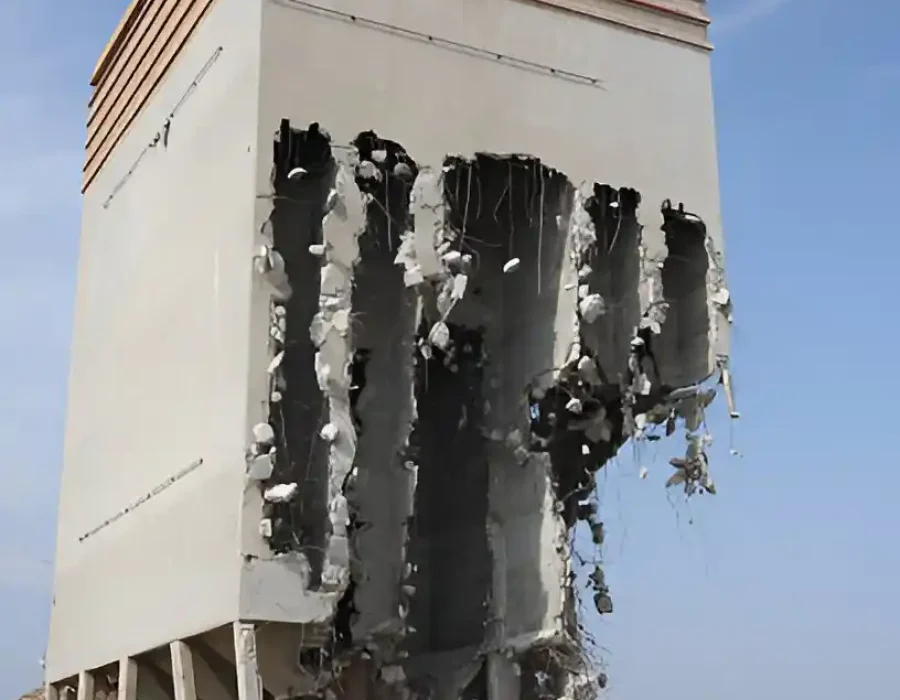Partially demolished concrete building with debris below.