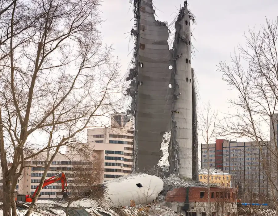 Partially demolished concrete tower, excavator, urban redevelopment site cleanup