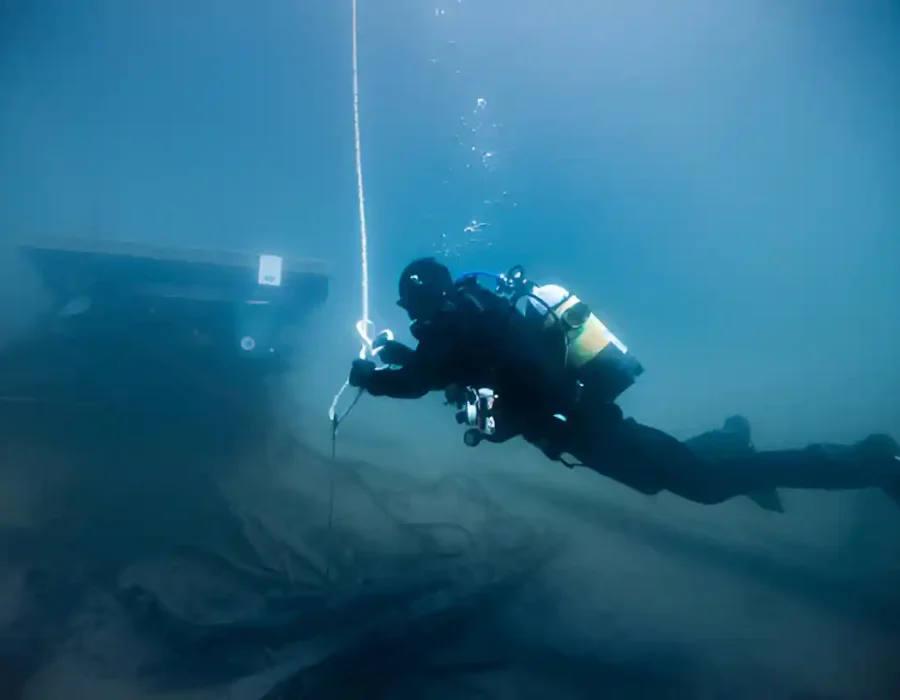 Scuba diver performing underwater demolition tasks with a rope.