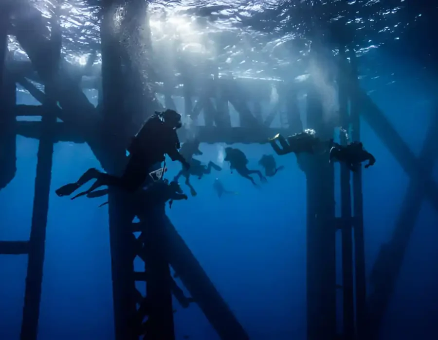 Multiple divers working near underwater industrial platform, marine construction site