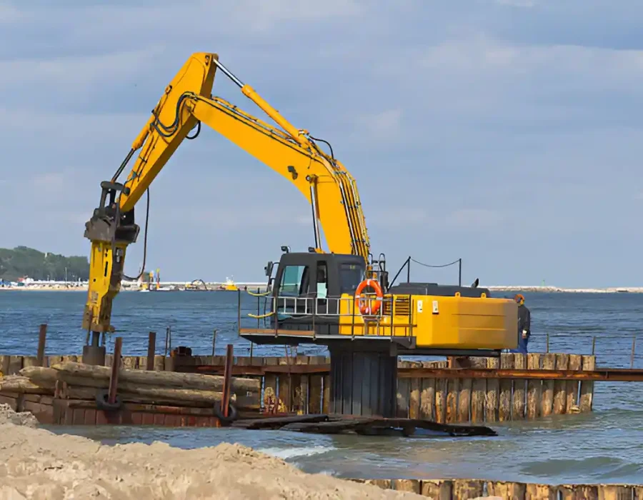 Excavator on water conducting marine demolition and debris removal near a shoreline.