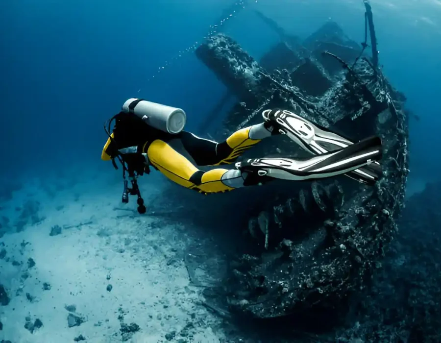 Scuba diver examining sunken vessel, professional marine demolition assessment