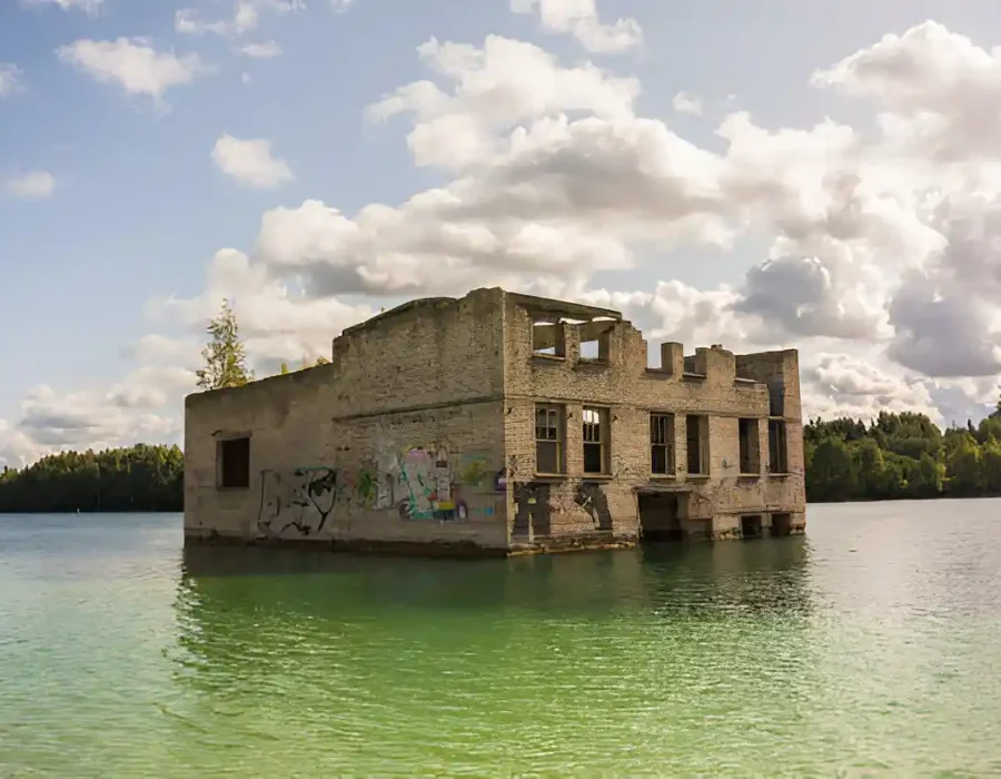 Flooded abandoned building surrounded by water and greenery