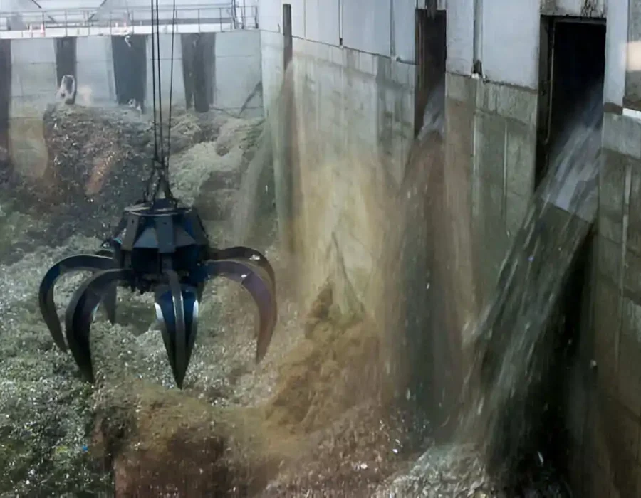 Mechanical claw grabber removing construction debris in concrete industrial setting